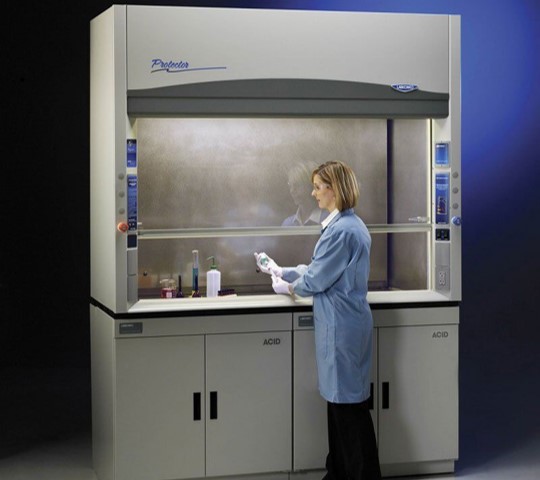 A Woman wearing Personal Protective Equipment performing an experiment in a laboratory fume hood
