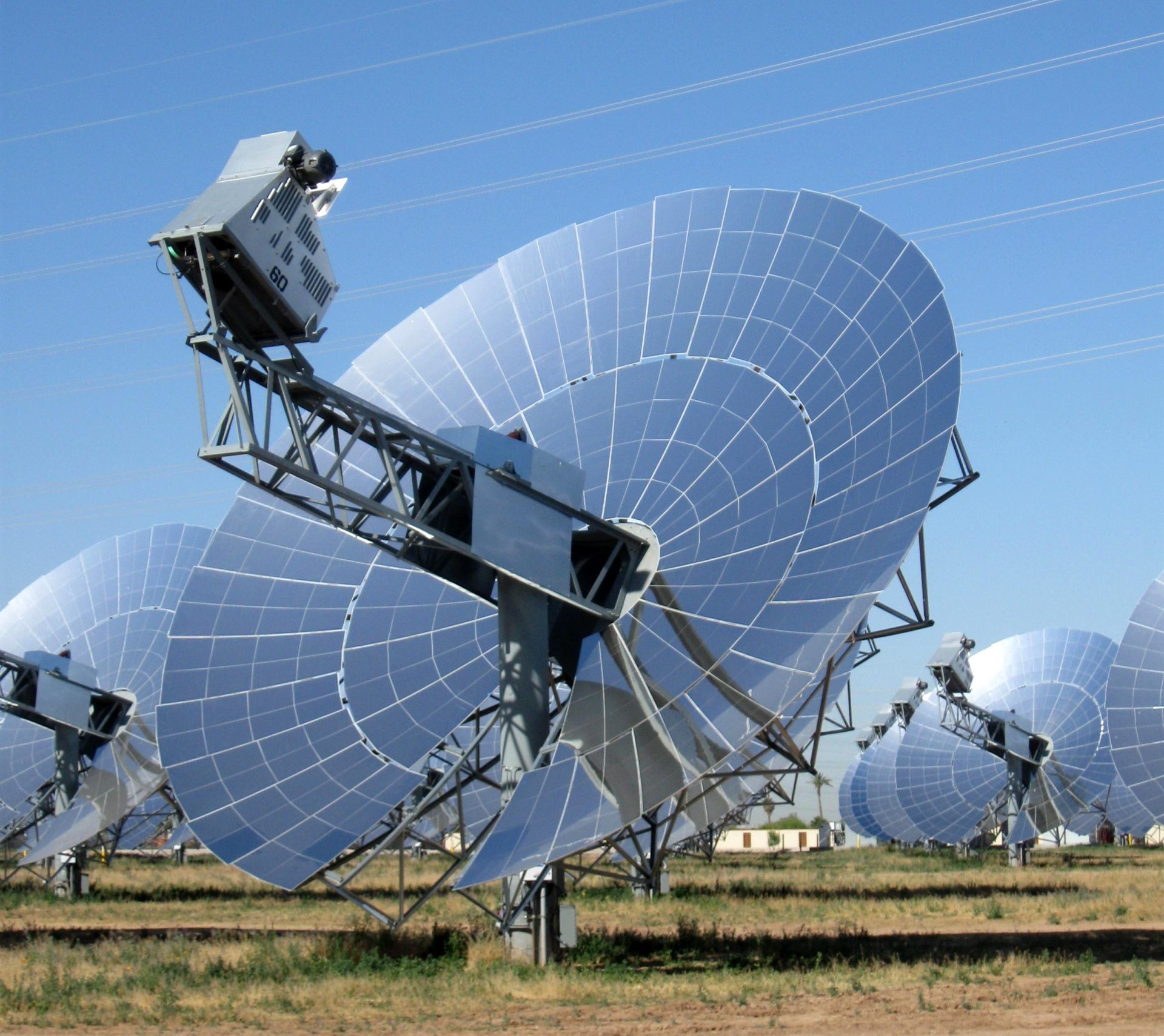 An Array of Dish-shaped Solar Arrays in a dirt and grass field